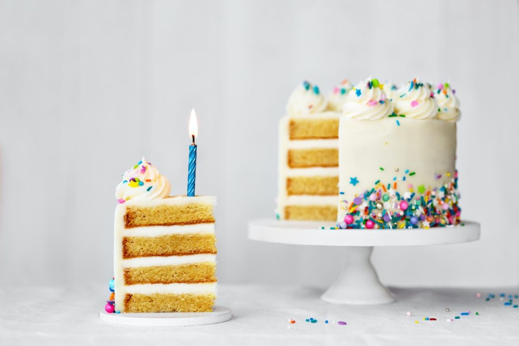 birthday cake with slice removed and blue birthday candle.jpg