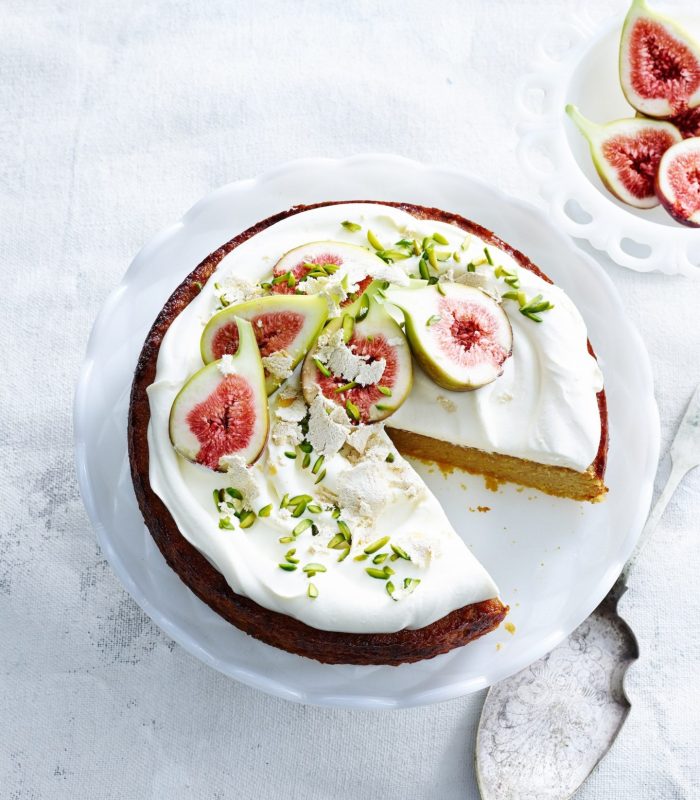 overhead view of orange and almond cake with yoghurt cream pistachios figs and cake server.jpg